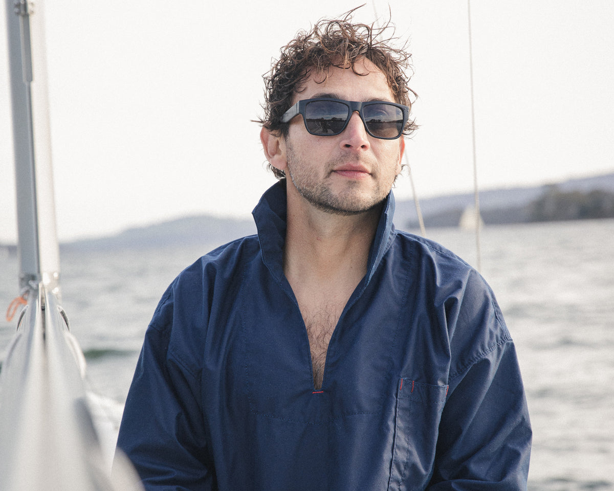 The Mariner's Smock in navy oilskin, worn at the helm of a sailing boat